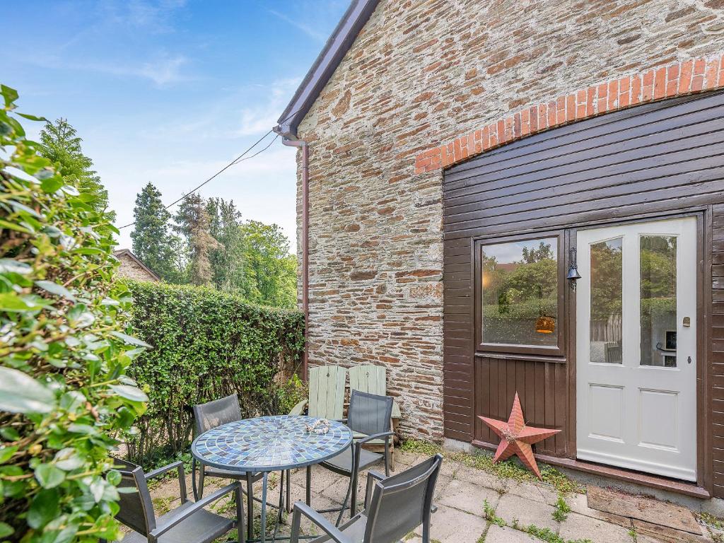 a patio with a table and chairs in front of a building at Gamekeepers Hide in Ivybridge