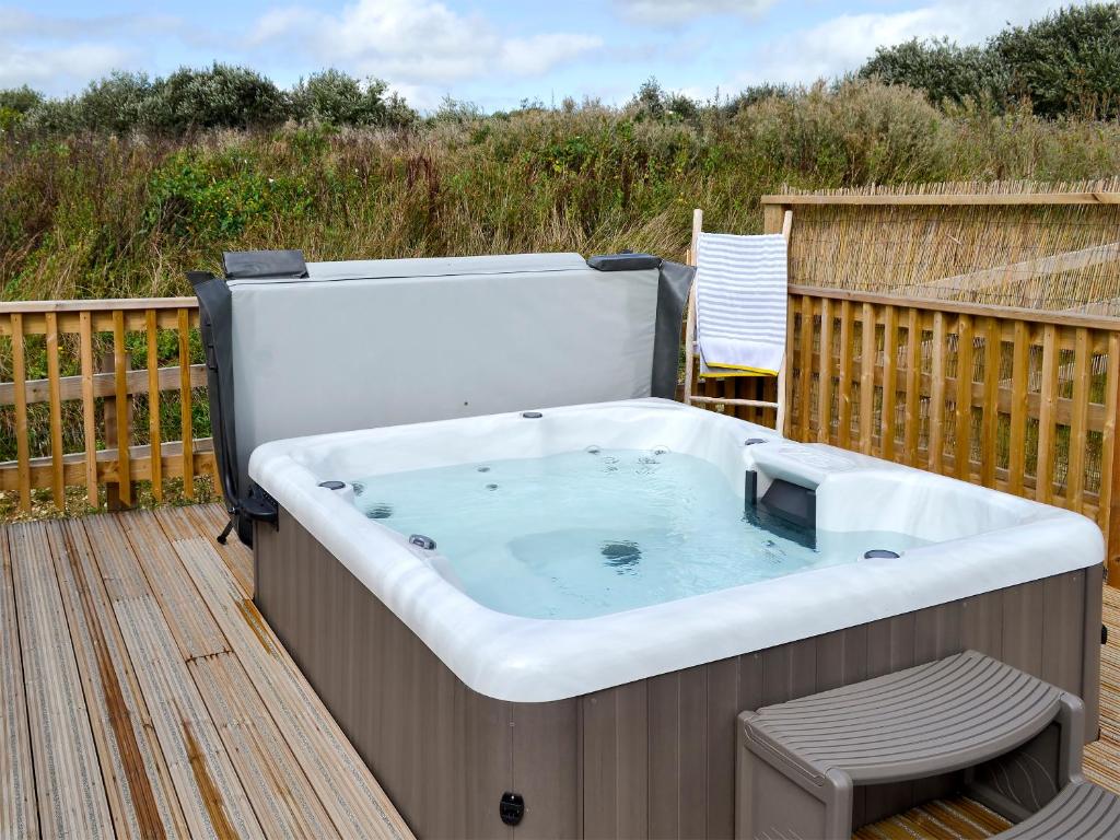 a hot tub on a deck with a chair at Hen Harrier Lodge-Uc3979 in Saint Columb Major