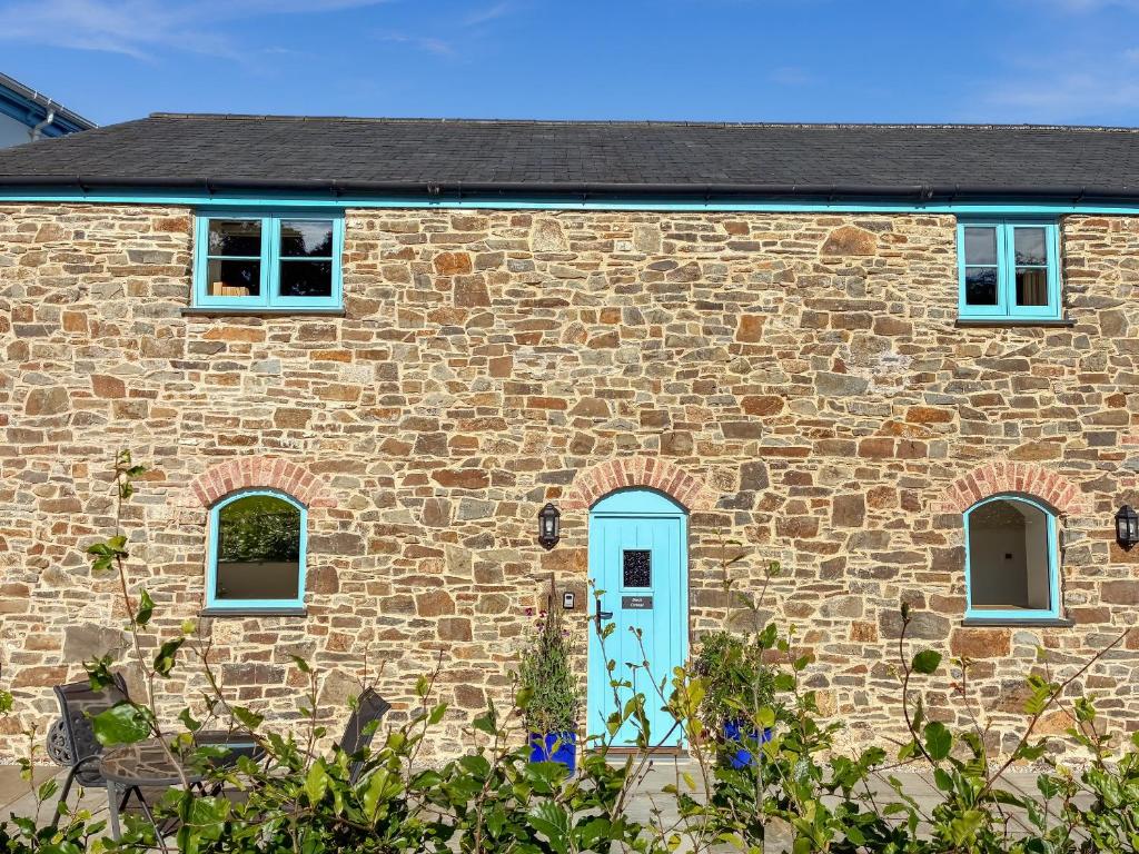 une maison en briques avec une porte et des fenêtres bleues dans l'établissement Beech Cottage - Uk49211, à Jacobstowe