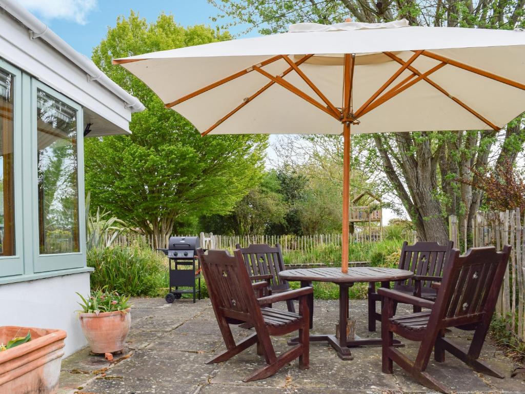- une table et des chaises sous un parasol sur la terrasse dans l'établissement Lomond Cottage, à Garsington