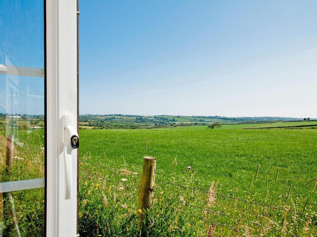 a open door to a field of green grass at Hawfinch Apartment - Uk49304 in Woolfardisworthy
