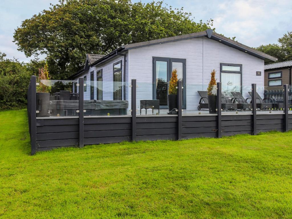 a small house with a black fence in a yard at Seagrass Lodge in Carnguwch
