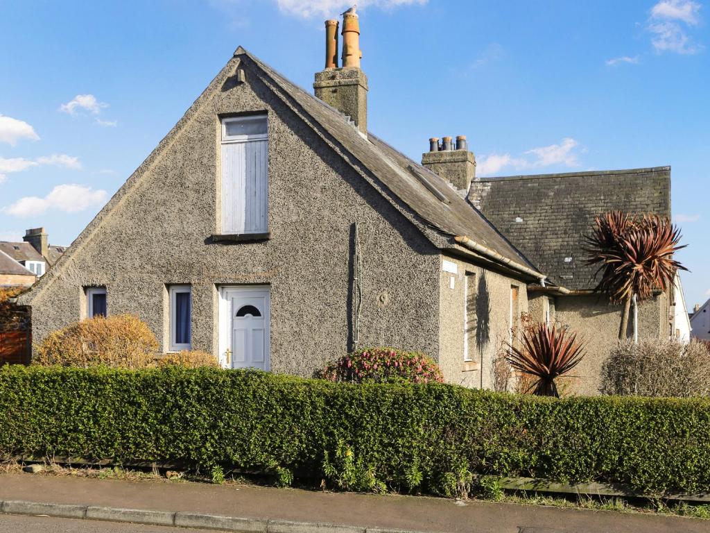 an old stone house with a window and bushes at Burnside Place in Cellardyke