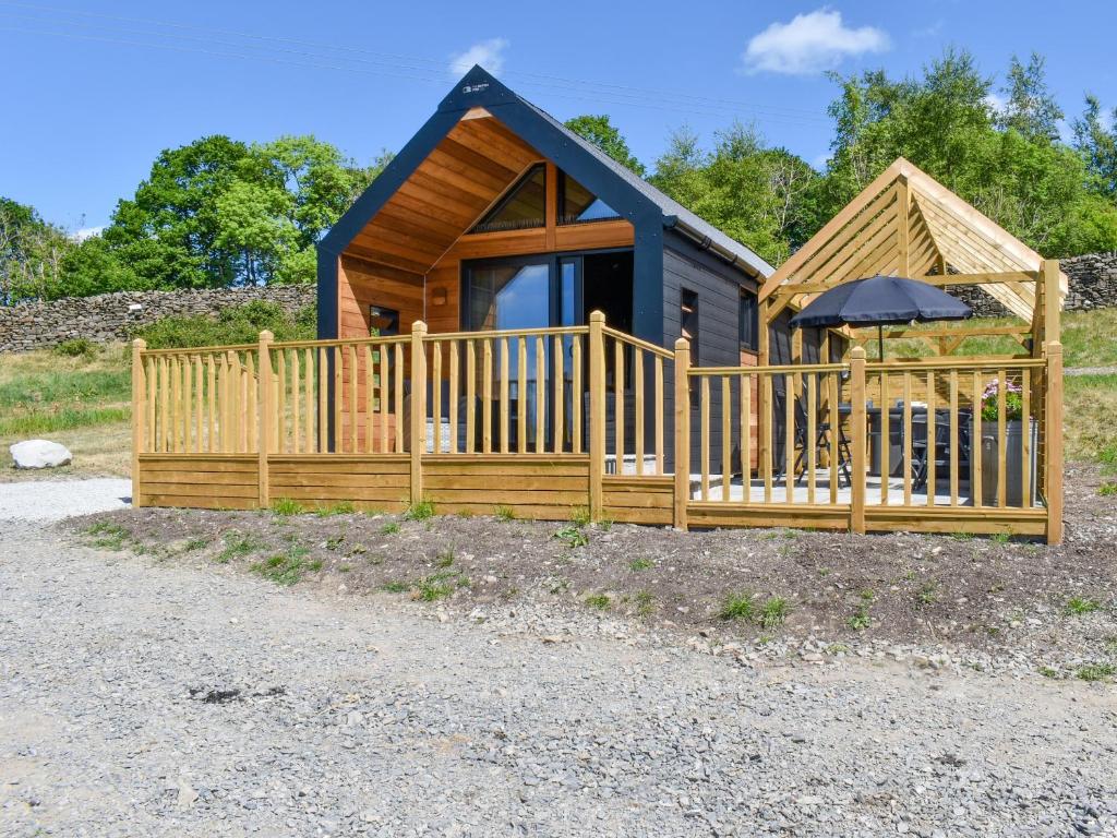 a cabin with a wooden fence and an umbrella at Yan - Uk49355 in Gatebeck
