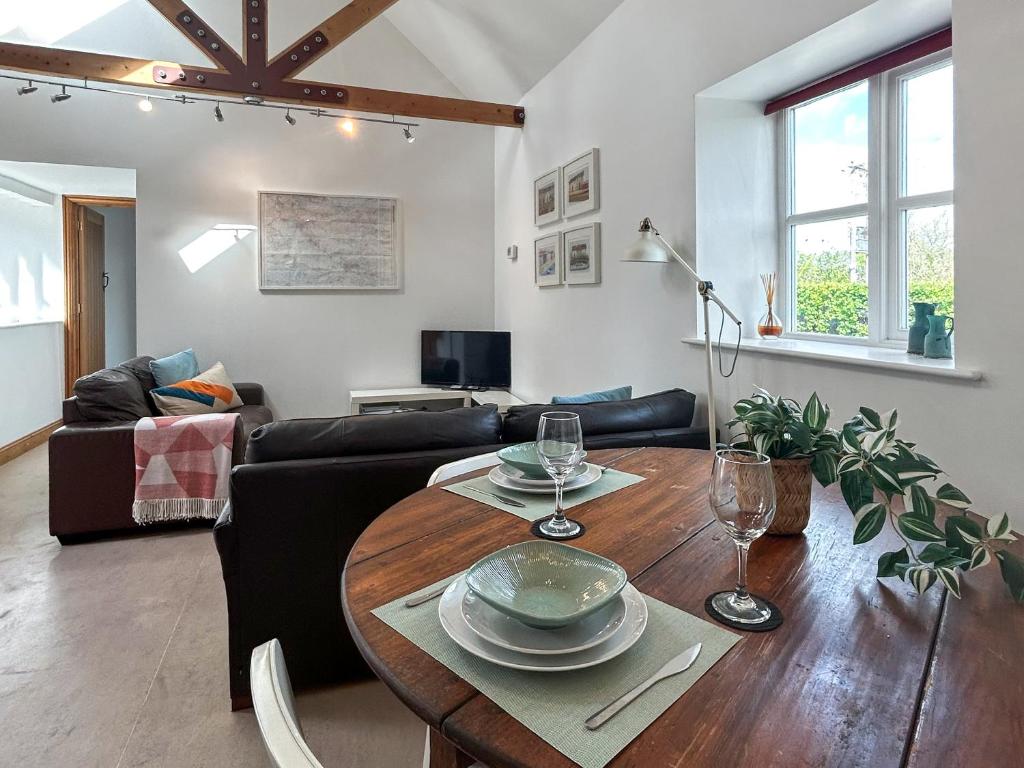 a living room with a wooden table with wine glasses at Noddingway Cottage in Weare