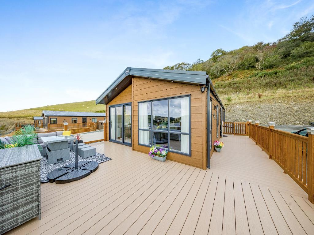 a wooden deck with a small cabin on the beach at Hillfort Lodge in Llanrhystyd