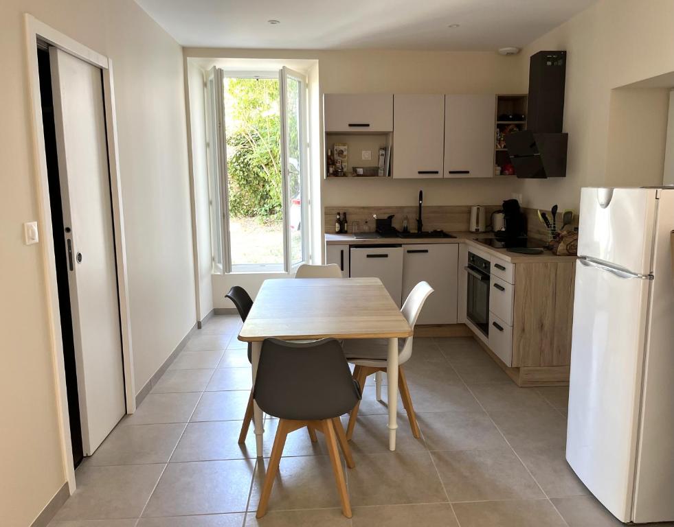 a kitchen with a wooden table and a white refrigerator at Meublé Voltour dans la Villa Denise in Vals-les-Bains