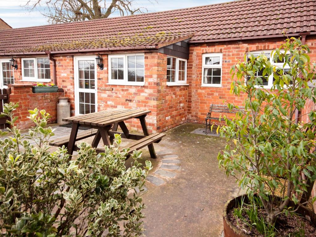 a wooden picnic table in front of a brick building at Brown Snout in Ledbury