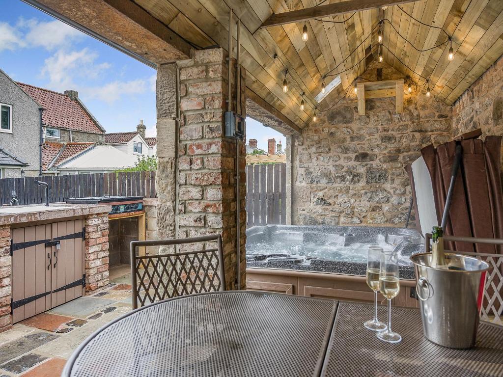 un patio esterno con tavolo e vasca idromassaggio di The Old Cottage a Beadnell