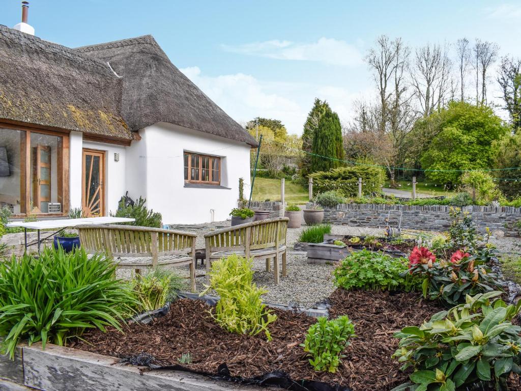ogród z ławkami przed domem w obiekcie The Thatched Cottage - Uk49600 w mieście Lifton