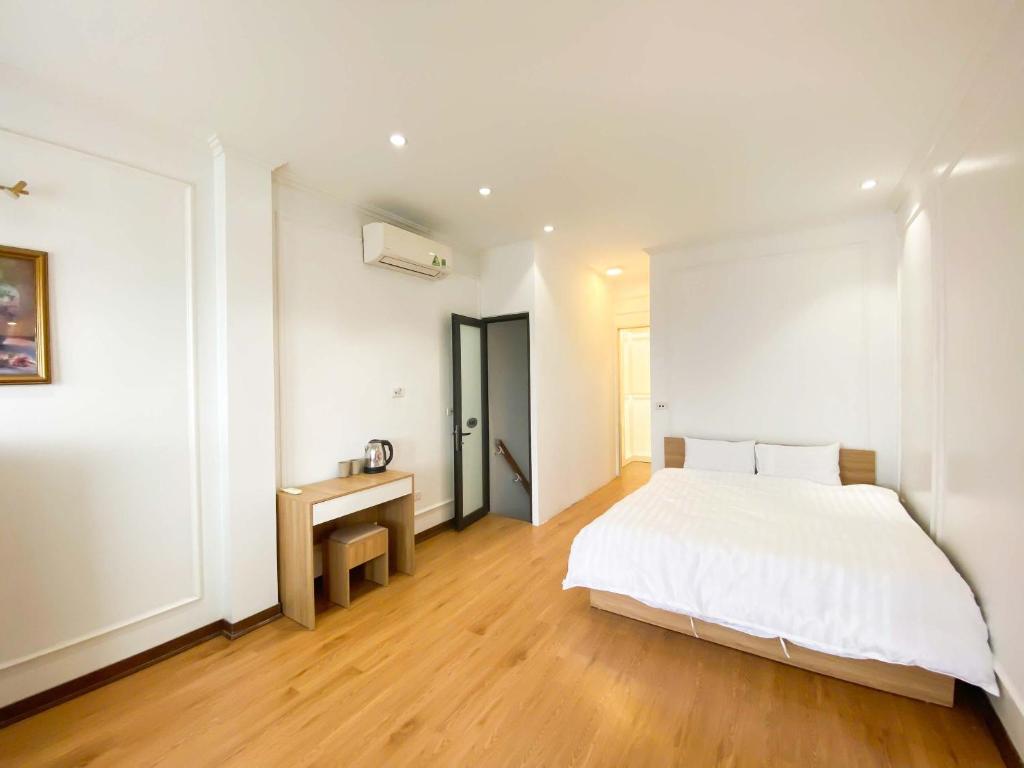 a white bedroom with a bed and a desk at Eco Hotel Tran Hung Dao - Old Quater in Hanoi