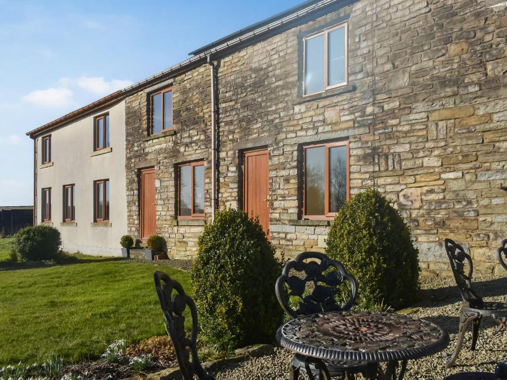 una casa in pietra con un tavolo e sedie di fronte di The Cottage At Peers Clough Farm a Rossendale