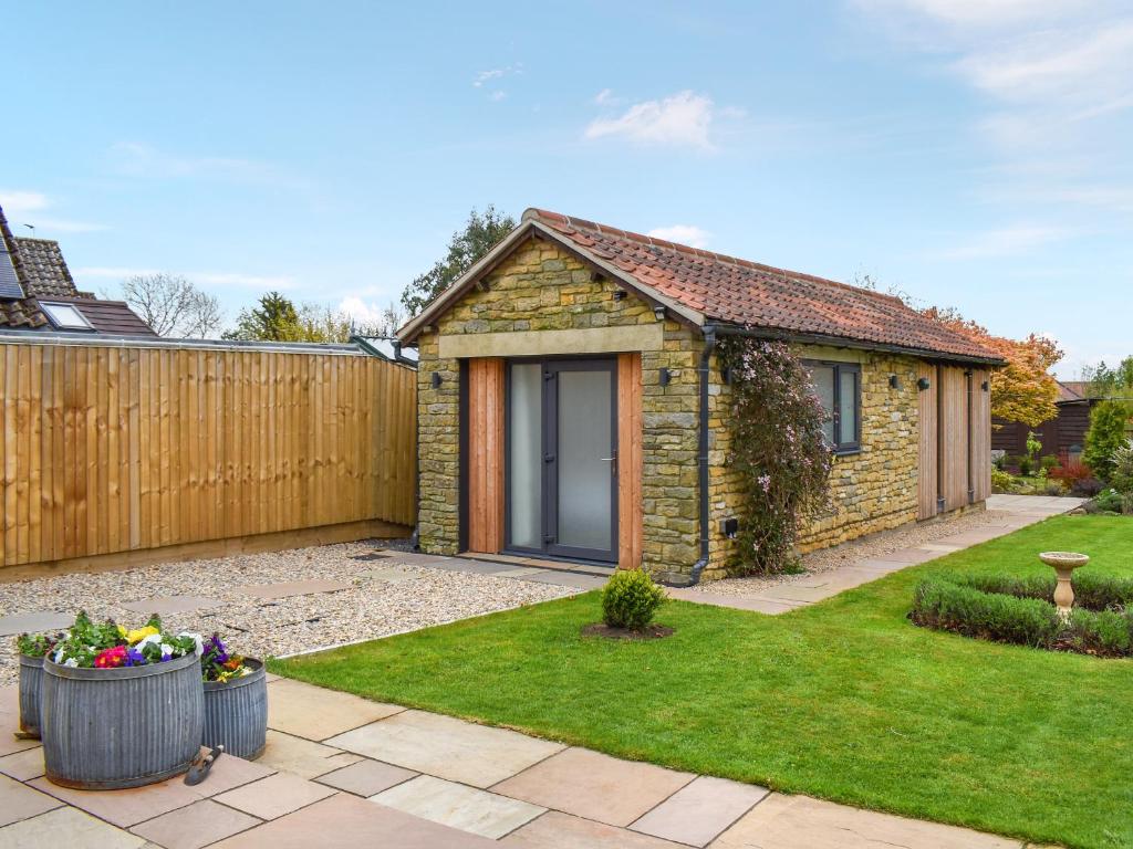 a stone house with a fence in a yard at Garden Cottage in Thornton Dale