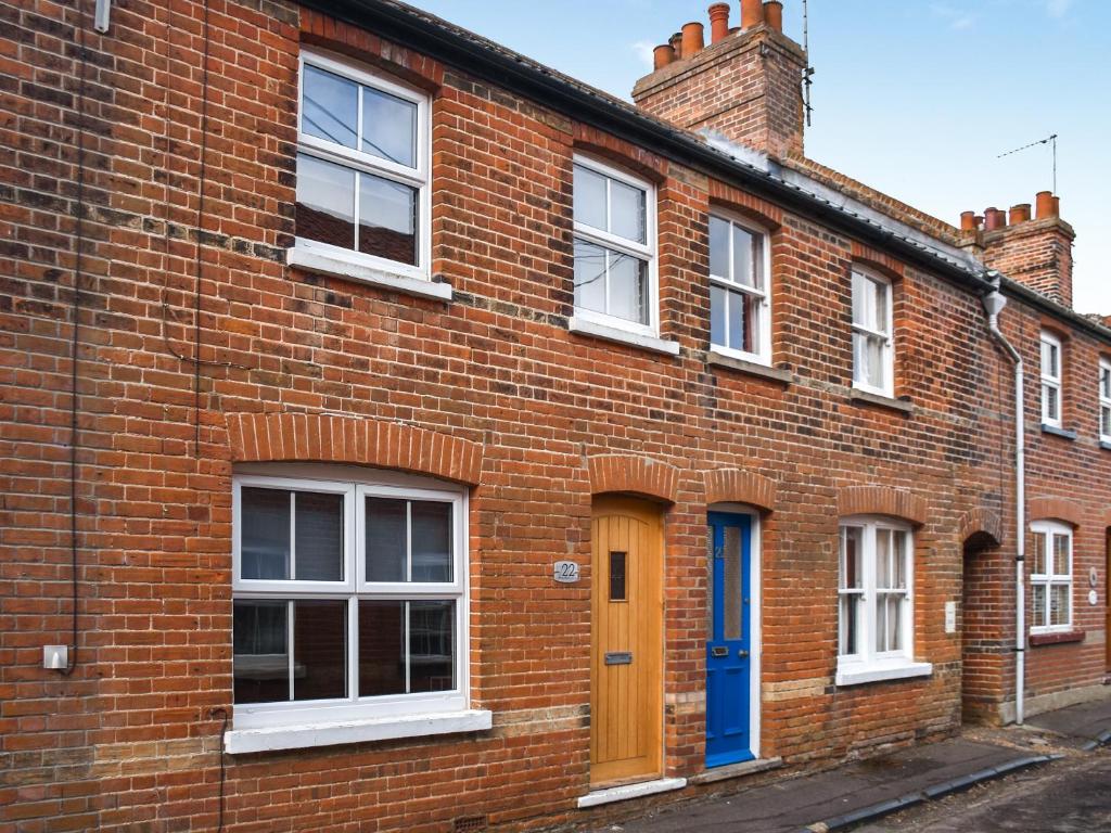 a red brick building with white windows and a blue door at Waverley Cottage in Mundesley