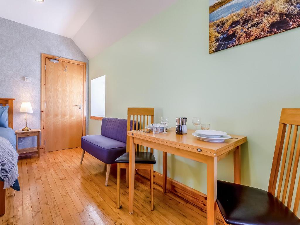 a dining room with a table and a blue chair at Quinag Studio Apartment - Uk49098 in Inchnadamph