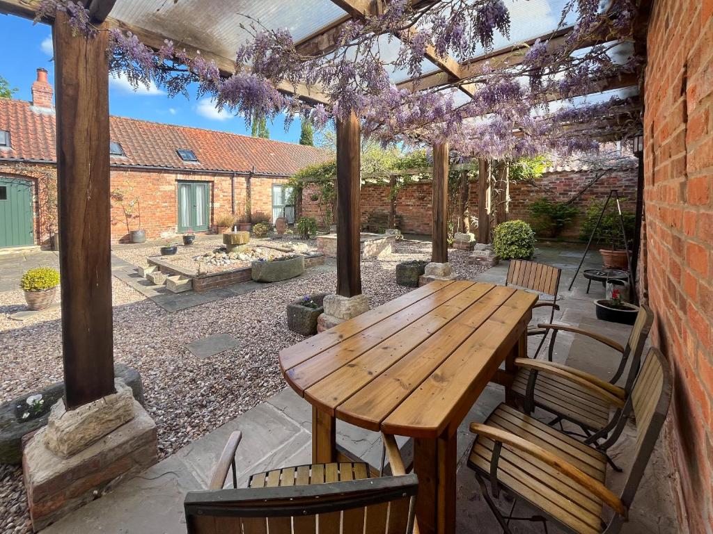 a patio with a wooden table and chairs at Meadow View Broadlea in Stokeham