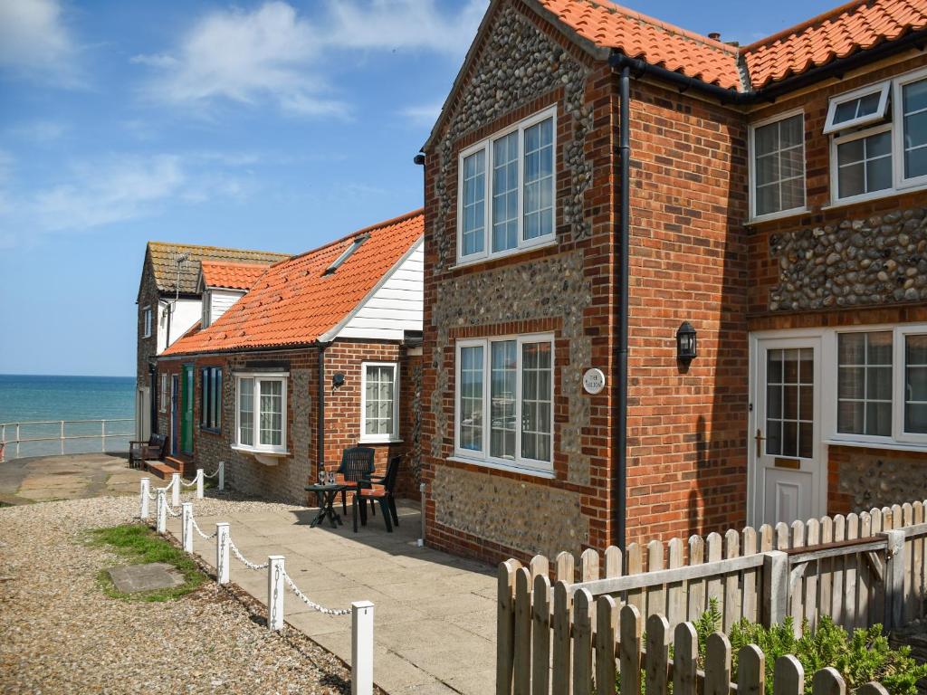 Una casa de ladrillo con una valla junto al océano. en The Hilton, en Sheringham