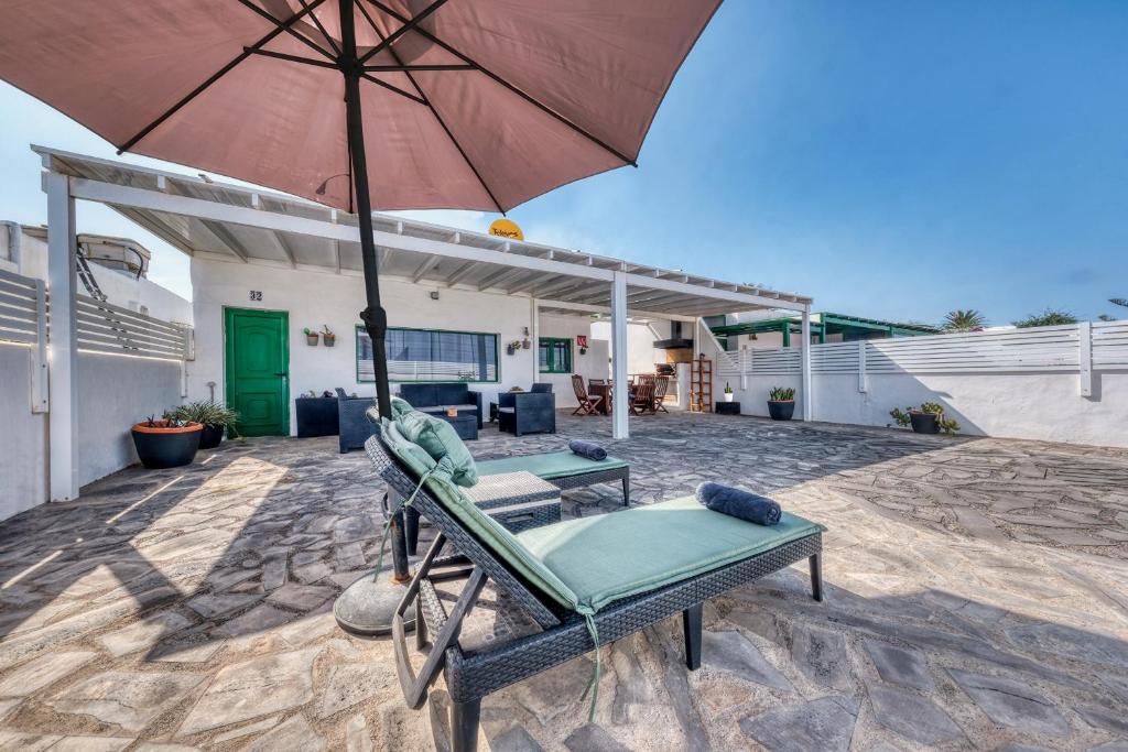 a patio with a chair and an umbrella at Cocoteros Ocean View House in Guatiza