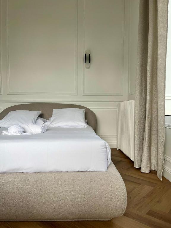 a bed with white sheets and pillows in a room at Suite Arche - Maison les Arcades au pied de la Gare de Charleville-Mézières in Charleville-Mézières