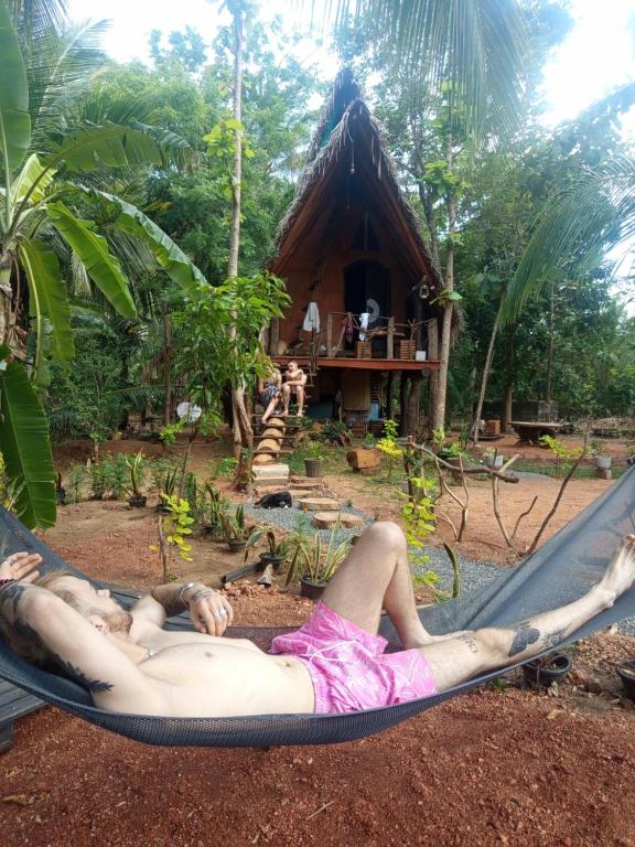 een vrouw die in een hangmat voor een hut ligt bij Sigiri Hunter's Eco Tree lodge in Sigiriya