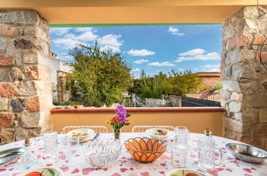 ein Tisch mit Tellern und Gläsern auf einem Balkon in der Unterkunft Casa Alva in Bari Sardo