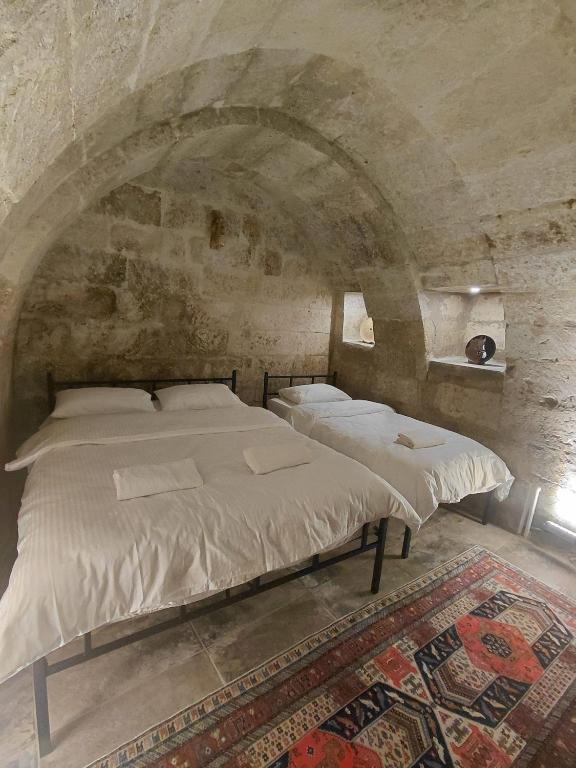 a bedroom with a large bed in a stone wall at Cappadocia Masuer House in Ürgüp
