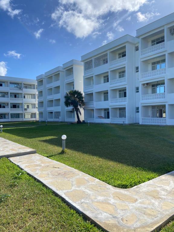a large white apartment building with a grass yard at Nautical Nest Apartments in Malindi