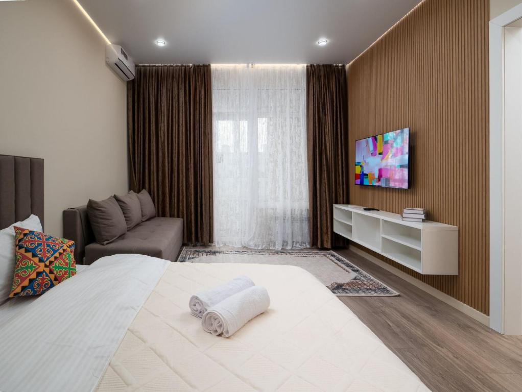 een slaapkamer met een groot bed en een tv aan de muur bij Everest Home in Alma-Ata