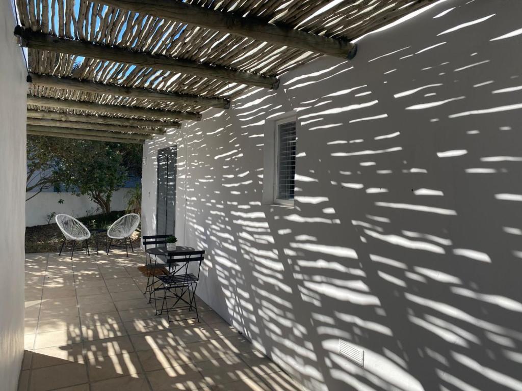 a patio with chairs and a table on a white wall at Namaste Cottage - Garden Facing 2-sleeper Hideaway in Paternoster
