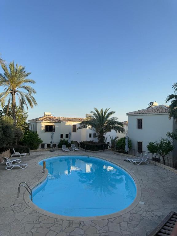 a large swimming pool in a courtyard with palm trees at Tranquil Poolside apartment with stunning views in Mazotos