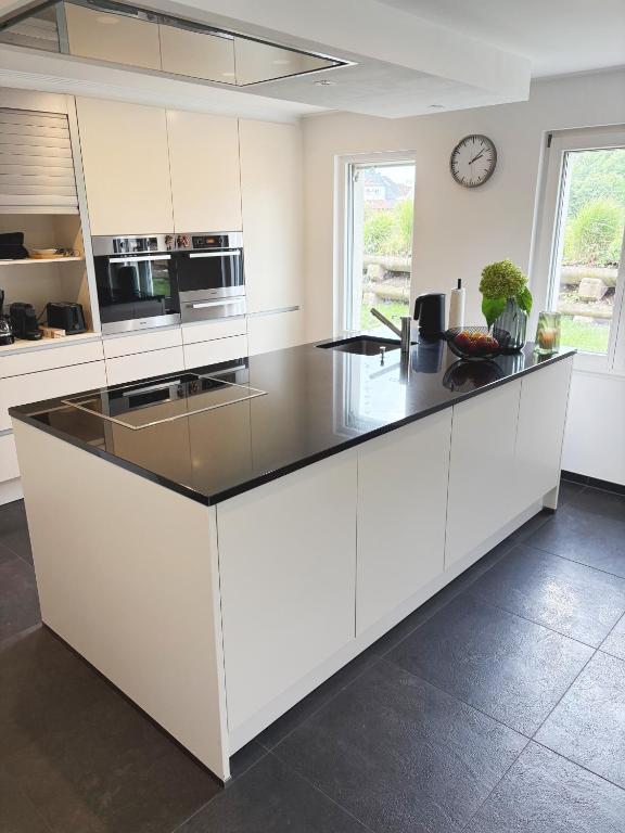 a kitchen with white cabinets and a black counter top at Ferienhaus Birds No 11 Lauchringen in Lauchringen