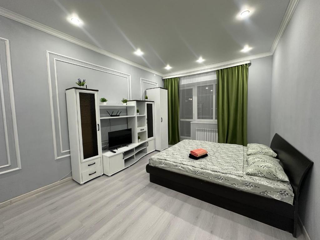 une chambre avec un lit et une télévision dans l'établissement Уютная 1 комнатная квартира в ЖК БАВАРИЯ, à Aqtöbe