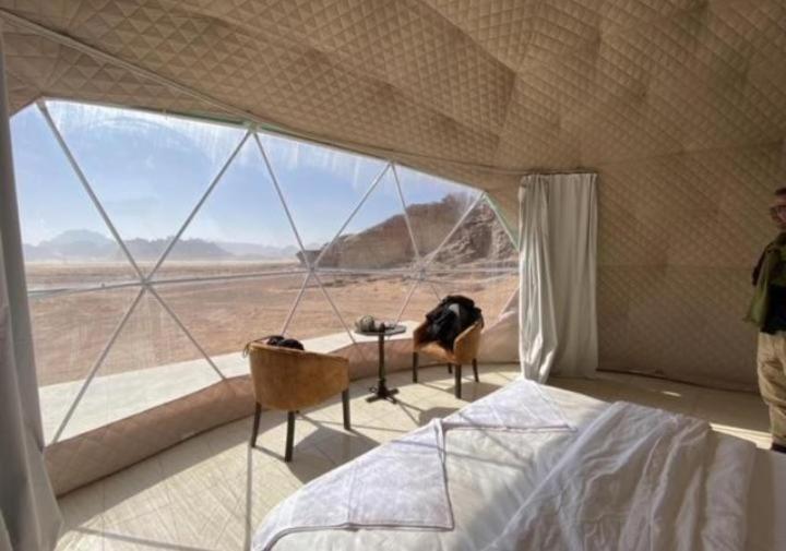 Un dormitorio con una cama y una ventana grande. en Wadi Rum Luxurious Camp View, en Wadi Rum