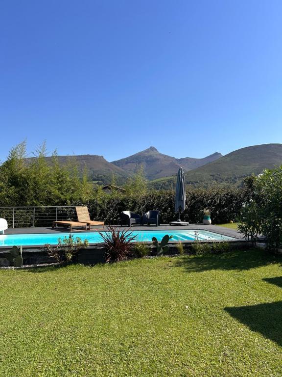 a swimming pool in a yard with mountains in the background at Chambre indépendante au pied de la Rhune in Urrugne