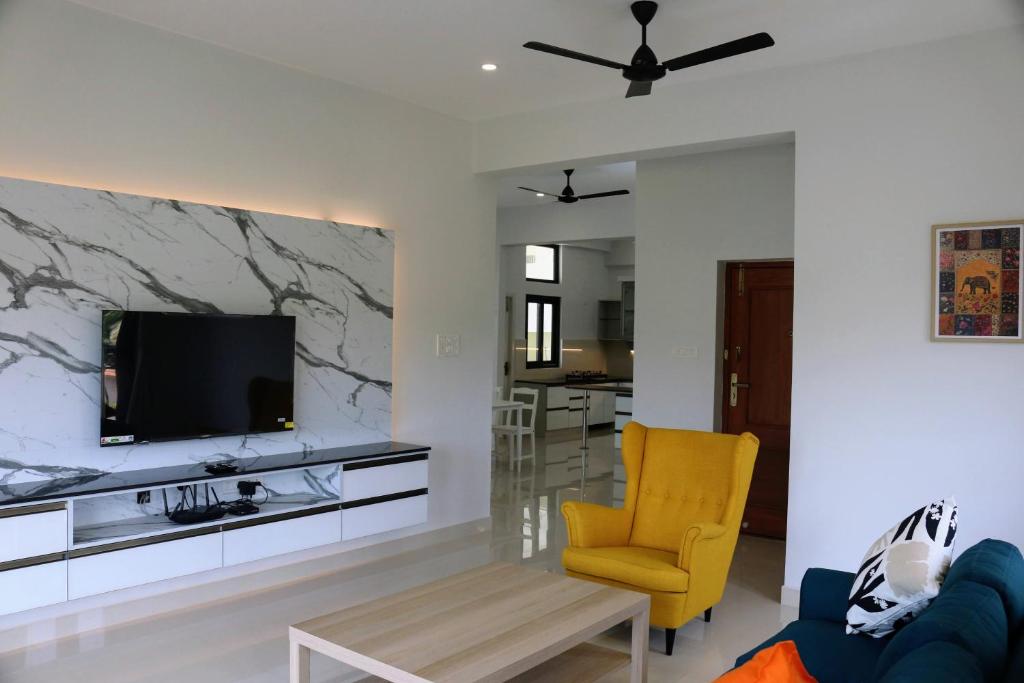 チェンナイにあるTara Spacious 3BHK Virugambakkamのリビングルーム(テレビ、黄色い椅子付)