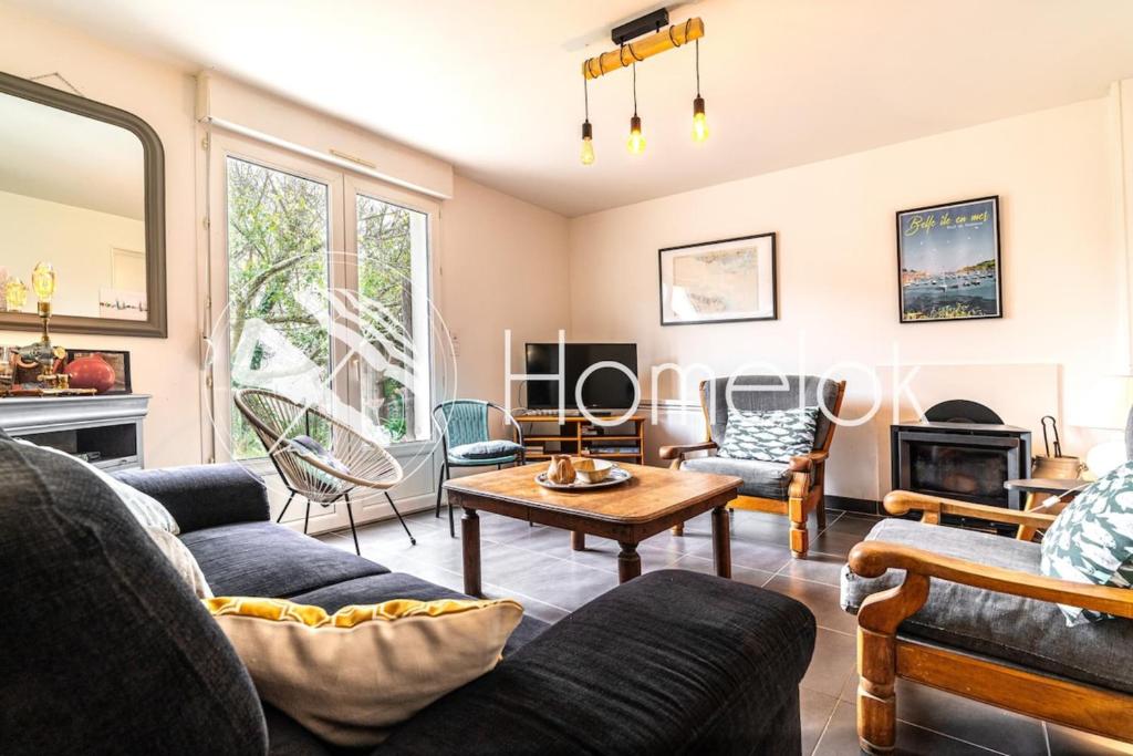 a living room with couches and a table at Maison lumineuse à 50m de la mer idéale en famille in Riantec
