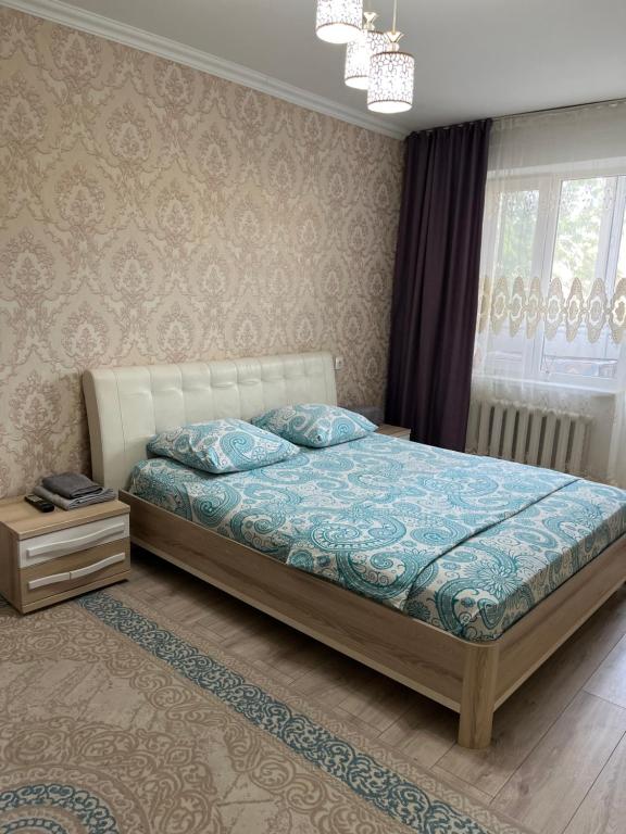 a bedroom with a bed with a blue comforter at Авангард 4-12 in Atyraū