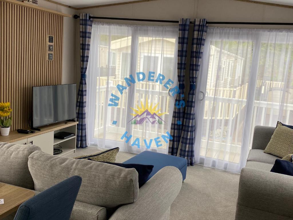 Una sala de estar con un sofá y un televisor. en Wanderers Haven, Brigham, Cockermouth, Cumbria, en Brigham