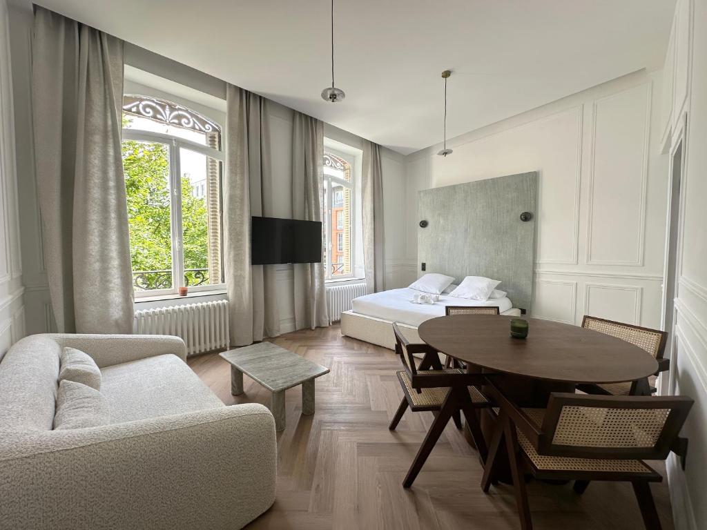 ein Wohnzimmer mit einem Bett und einem Tisch in der Unterkunft Suite Brume - Maison les Arcades au pied de la gare de Charleville-Mézières in Charleville-Mézières