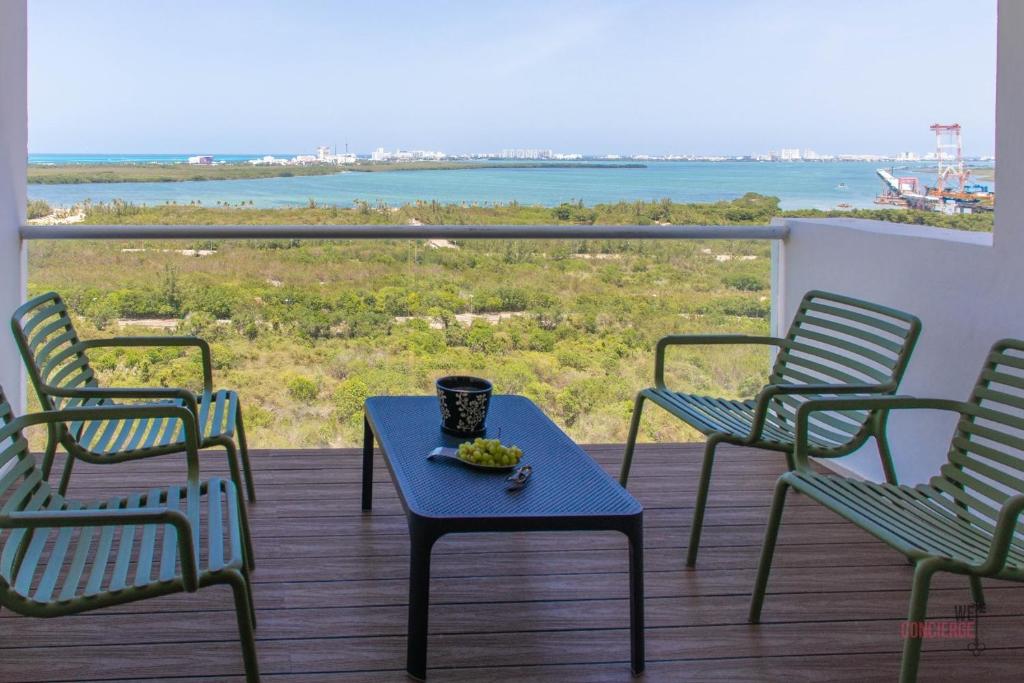 three chairs and a table on a balcony with a view of the ocean at Condo Blue Lagoon Cancun-Espectacular Vista in Cancún