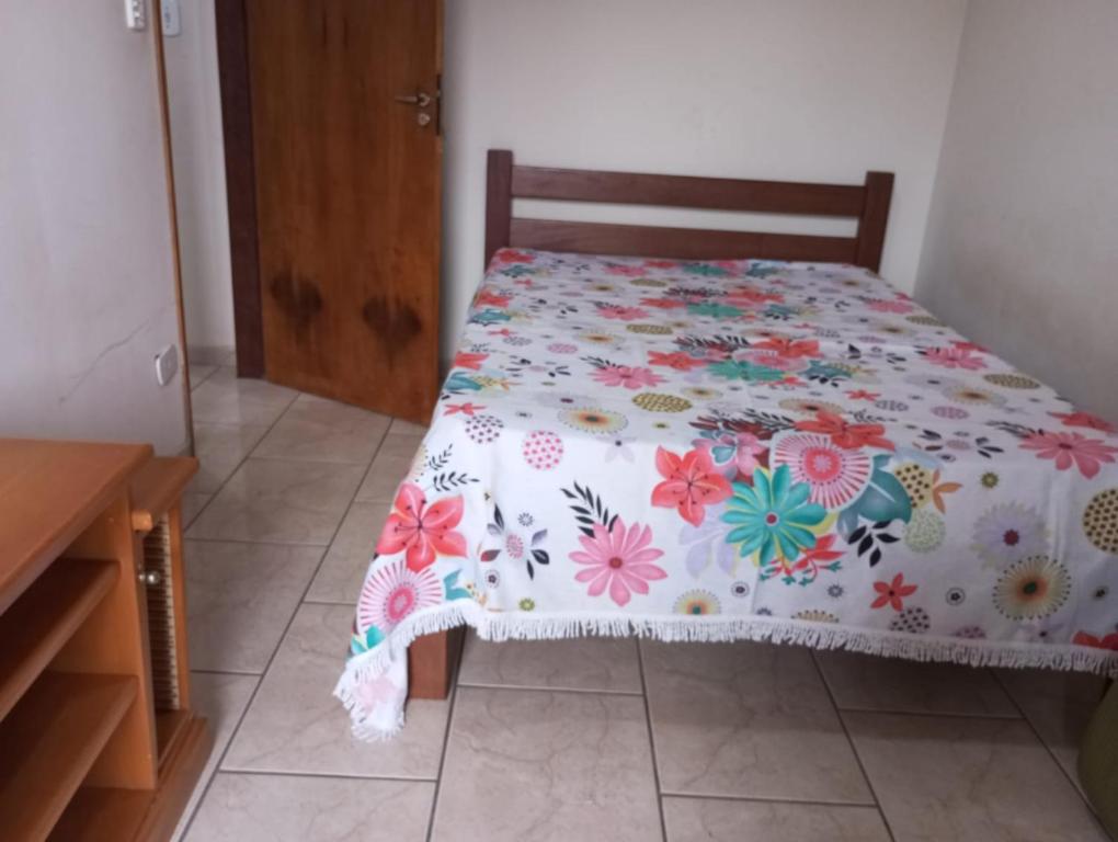 Cette chambre comprend un lit avec un couvre-lit floral. dans l'établissement que delicia de lugar, à Itanhaém