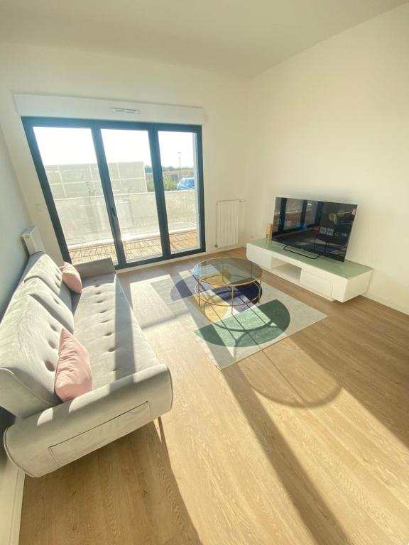 a living room with a couch and a glass table at Appartement T2 cosy au calme in Épinay-sur-Orge