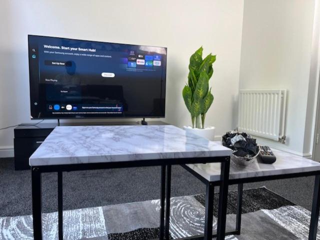 a living room with a table with a large screen tv at Home In Maidstone in Maidstone