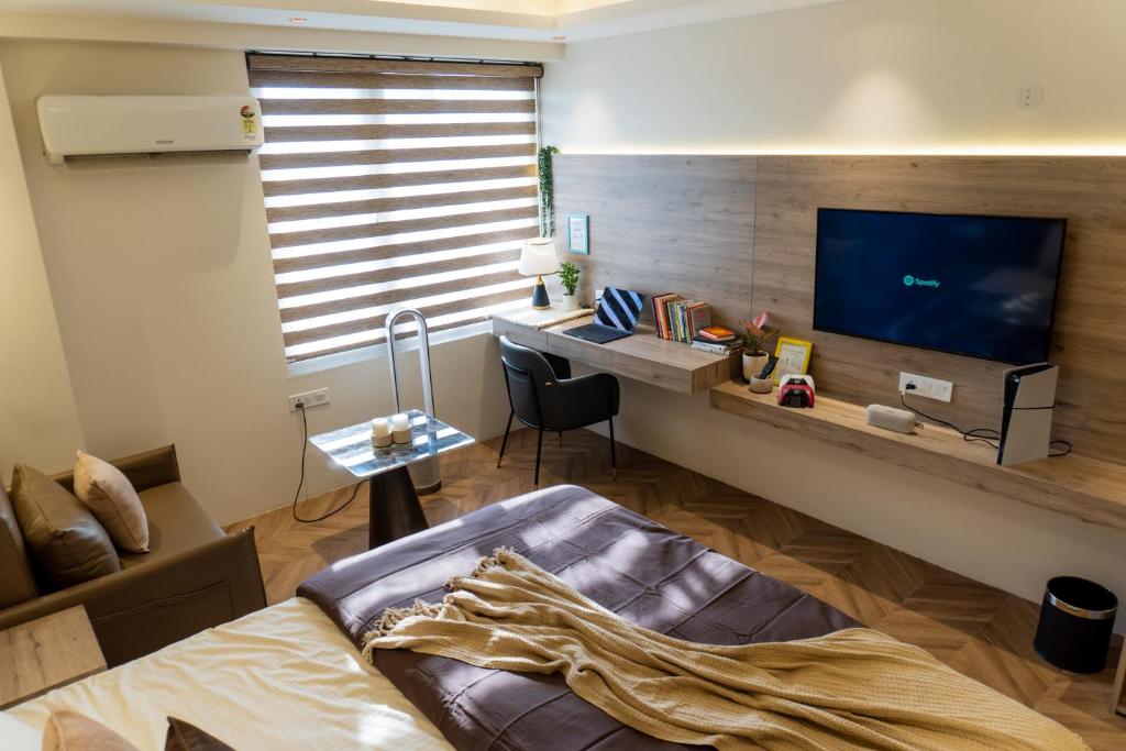 a bedroom with a bed and a desk with a television at Stylish & Comfortable Studio near Expo Center Greater Noida opposite Metro in Greater Noida