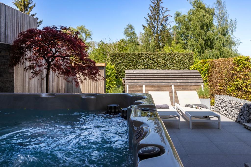 a hot tub in a backyard with a bench at Vakantiewoning Relax Ohm in Zottegem