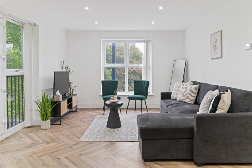ein Wohnzimmer mit einem grauen Sofa und zwei grünen Stühlen in der Unterkunft 2 Bed Apartment Near City Centre - on street parking in Birmingham