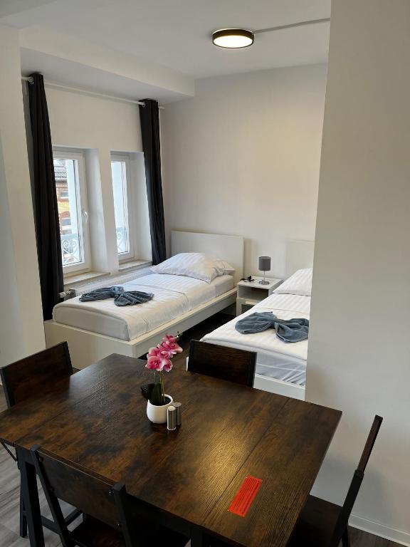 a room with two beds and a table with flowers on it at CityStay Bergisch Gladbach in Bergisch Gladbach