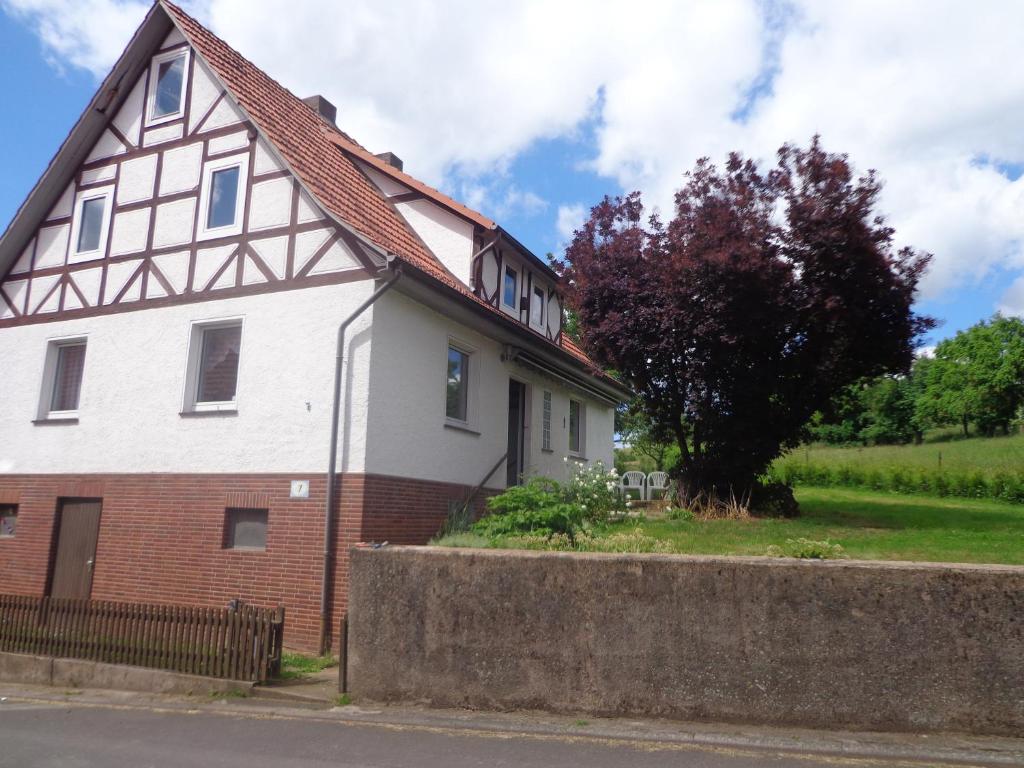 una casa blanca con techo marrón y árbol en Ferienhaus van Wijk, en Obergude