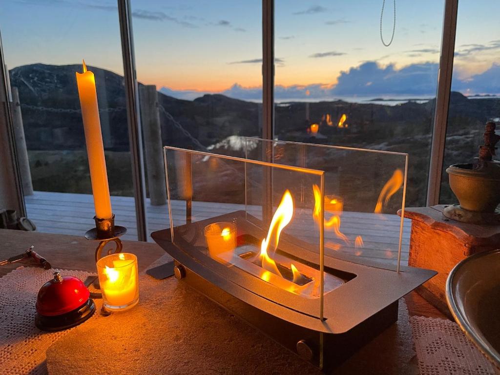 a fire pit with candles on a table in front of a window at Cabin with stunning views and outdoor jacuzzie in Leset