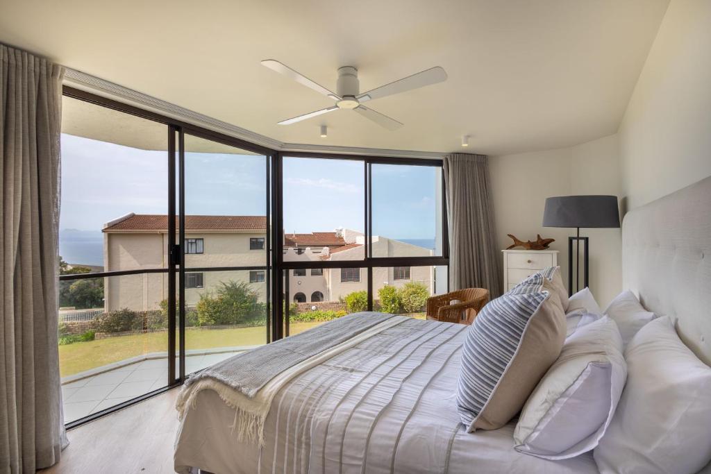 a bedroom with a bed and a large window at Seascape Plettenberg Bay in Plettenberg Bay